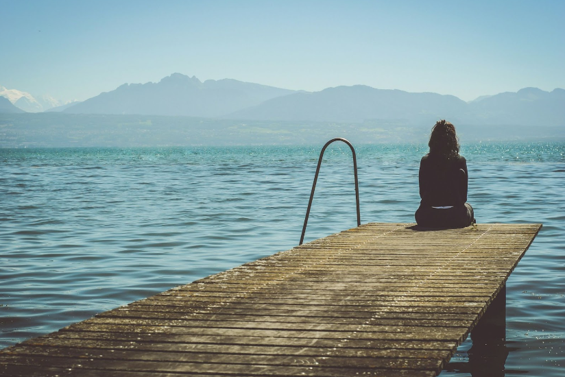 Women sitting at the end of a wooden jetty and hills in the background. Hypnotherapy for Depression